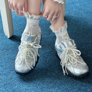 Baskets argentées avec lacets en perles et chaussettes blanches en dentelle sur tapis