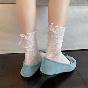 Detail of white lace mesh calf socks with silk bow accent paired with blue flats