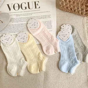 Detail of five pairs of pastel lace cotton socks with KIKI SOX heart tags on woven rug