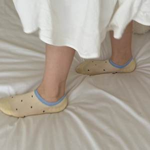 Detail of yellow polka dot boat socks with blue elastic cuff on comfortable model feet