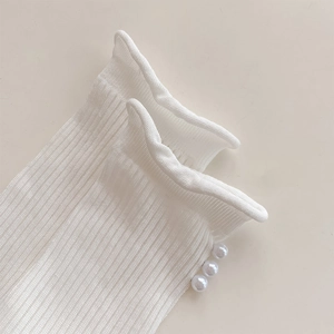 Detail of white ribbed crew socks featuring three elegant pearls on the ruffled cuffs