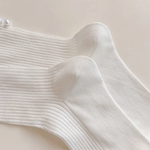 Detailed view of white ribbed knit socks with elegant pearl accents on the heel area