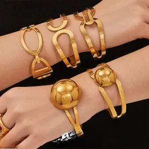 Detailed close-up of multiple gold geometric bracelets on wrist with bold street style