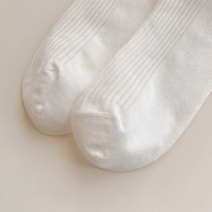 Detailed close-up of white ribbed knit ballet socks with elegant pearl heel embellishment