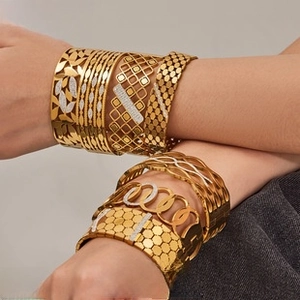 Detailed view of stacked vintage 18K gold-plated titanium steel bangles with diverse patterns