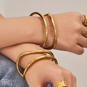 Detail shot of a minimalist gold irregular ripple bangle and textured open ring set