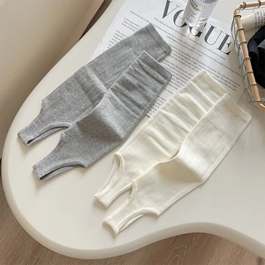 Detailed knit texture of grey and off-white stirrup leg warmers with vertical ribbing