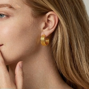 Detail of vintage textured gold hoop earrings with embossed dots on a model's ear