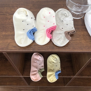 Detail of five pairs of polka dot cotton ankle socks in assorted pastel colors on wood