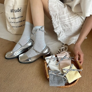 Détail de nœuds floraux sur des chaussettes en résille de diverses couleurs pastel