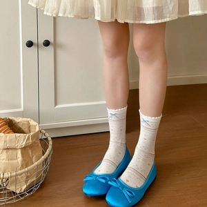 Detailed view of cream lace socks with blue bows and ballet flats for little girls
