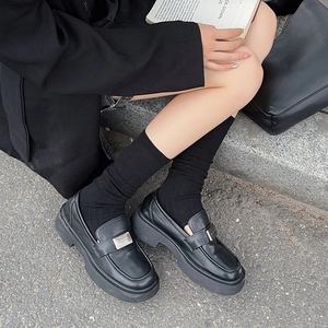 Detail of black matte platform loafers with metal buckle and ribbed leg warmers