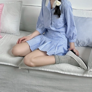 Close-up of blue and white striped shirt with a 3D flower detail and pleated skirt