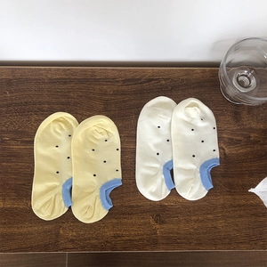 Detailed view of yellow and white polka dot cotton boat socks with blue heel patches