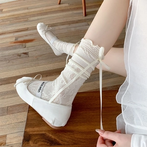 Détail de chaussettes en dentelle blanche avec nœuds et chaussures ballerines