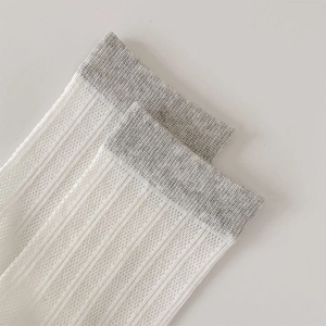 Close-up of white ribbed mesh socks with grey trim detail and breathable fiber texture
