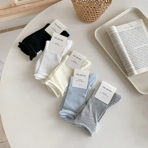 Detail of five pairs of cotton socks with pearl accents and ribbed texture on a white table