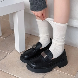 Close-up of black platform loafers paired with white ribbed knit stirrup leg warmers