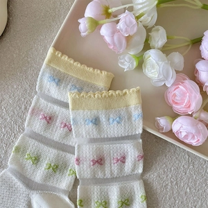 Detail of white mesh crew socks with colorful embroidered bows and yellow ruffled cuffs
