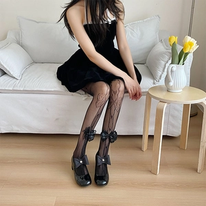 Detail of black hollow floral patterned lace tights with 3D bow accent and Mary Jane shoes