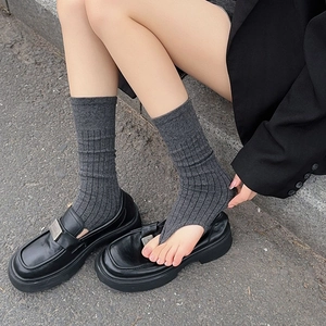 Detail of dark grey ribbed stirrup leg warmers paired with black leather loafers outdoors