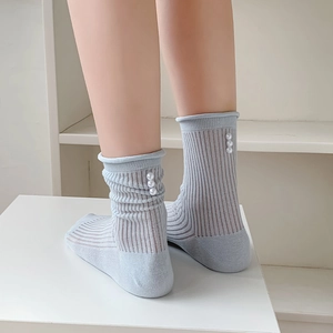 Detail of light blue ballet-style socks featuring elegant white pearl embellishments