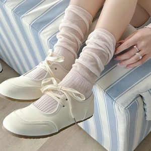 Close-up of ballet style beige slouch socks paired with white Mary Jane flat shoes