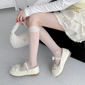 Detail of cream patent Mary Jane shoes with lace and bow on Lolita knee high socks