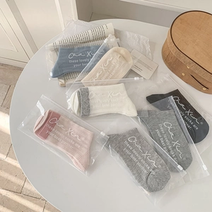 Detailed view of six pairs of casual ribbed socks in individual zipper bags on a desk