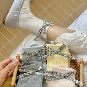 Détail de chaussettes à nœuds floraux et bords volantés en couleurs pastel