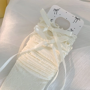 Détail de chaussettes en dentelle blanche avec nœuds en satin sur carte support