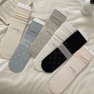 Detail von sechs hohlgestrickten Baumwollsocken in verschiedenen Pastellfarben auf Stoff