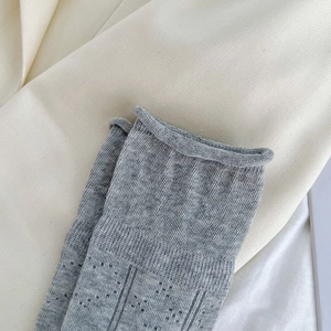 Detailed macro view of grey knit socks featuring openwork mesh and rolled cuffs