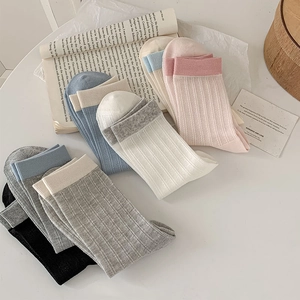 Detail showing various pastel ribbed knit socks with contrasting color cuffs on white surface