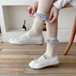 Gros plan de ballerines blanches avec nœud et sangle élastique logotypée au pied