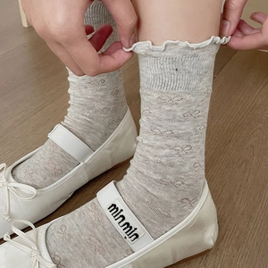 Detail of light gray mesh socks with bow jacquard and frilly ruffle cuffs on white shoes