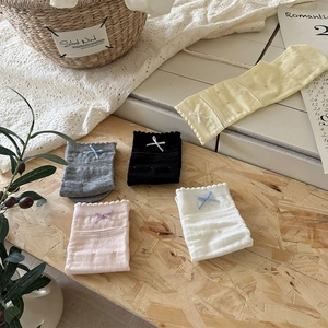 Detail of sweet lace-trimmed socks with bow accents in five pastel colors on wood table