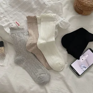 Detail of ruffle cuff socks with retro argyle pattern in neutral tones on white fabric