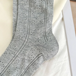 Close-up of grey pointelle knit socks with heart hollow pattern and soft texture