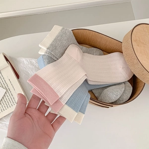 Detail of soft pastel cotton socks featuring rib knit texture and color-block cuffs
