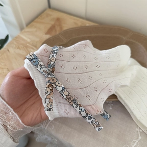 Détail de chaussettes en maille crème avec nœud floral et tricot ajouré respirant