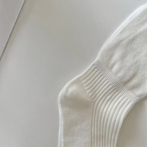 Close-up of white ribbed knit socks showing durable reinforced heel and elastic cuff