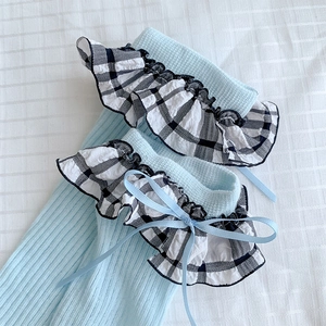 Détail de chaussettes bleu clair à côtes avec bordure volantée à carreaux et nœud