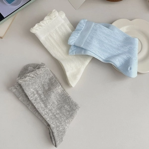 Detailed view of ruffle cuff socks in cream, light blue, and grey with argyle knit patterns
