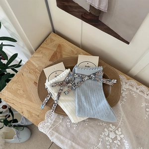 Détail de chaussettes en résille à nœud floral et bordure dentelle en blanc et bleu