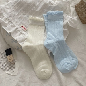 Detailed knit pattern of beige and light blue mid-calf socks with ruffle lace cuffs