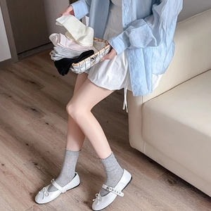 Détail de chaussettes grises à bordure dentelle avec chaussures Mary Jane blanches