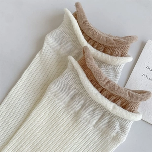 Detailansicht von cremefarbenen Socken mit vertikalen Rippen und braunem Wellensaum