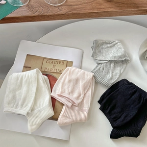 Flat lay of four pairs of ribbed knit socks in white, pink, grey and black colors