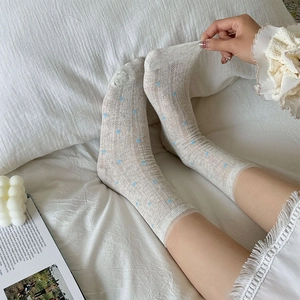 Close-up of beige mesh crew socks with blue polka dots and delicate lace trim detail
